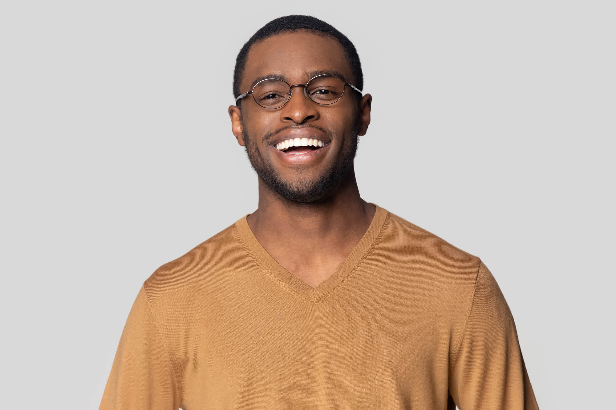 Head shot close up portrait happy smiling african american man in casual sweater looking at camera. Cheerful millennial black guy in round glasses posing for photo, isolated on grey studio background. Photo taken in Lisle, IL